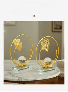 Detailed close-up of golden metal ginkgo leaf ornament with a crystal ball and glass base