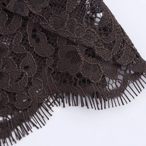 Close-up of intricate floral lace fabric in dark brown with delicate eyelash fringe edges