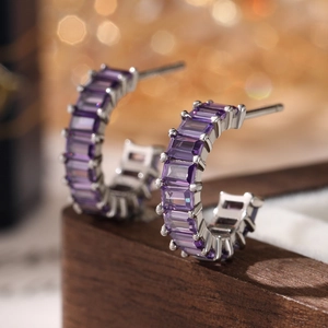 Detailed macro view of C-shaped 925 silver earrings with radiant purple square zircon stones