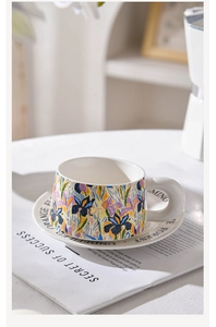 Macro detail of floral ceramic coffee cup with iris patterns and lettered saucer