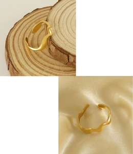 Detailed view of 18K gold plated stainless steel wave ring on wood and satin textures