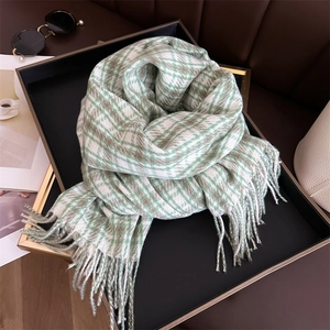 Detail of green and brown plaid cashmere-feel scarf with fringes on a luxury tray