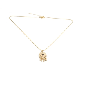 Detail view of gold evil eye pendant with blue zircon stone and teardrop charms on box chain