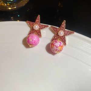 Detail of pink star earrings with pearls and marble beads on a white tray backdrop