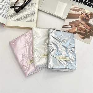 Quilted bow passport holders in pink, white, and silver with embroidery on white desk