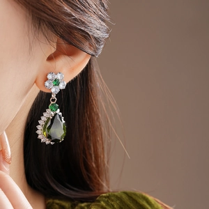 Macro view of flower-shaped earrings with green pear-cut zircon and silver finish