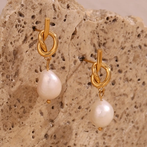 Macro shot of 18K gold-plated knotted stud earrings featuring irregular freshwater pearls