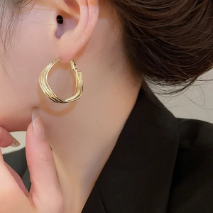 Close-up of elegant gold irregular twisted geometric hoop earrings on female model