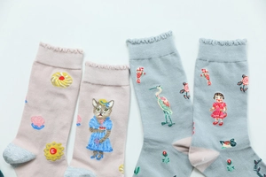 Detail of ruffled cuffs and embroidery featuring cats and birds on cotton socks