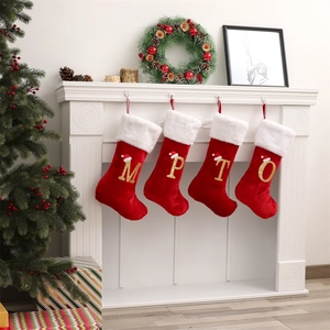 Dettaglio di calze di Natale rosse con lettere dorate M, P, T, O sul camino bianco