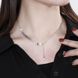 Close-up of silver wheat ear necklace with white pearls on a model's neck