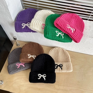 Detailed display of assorted knit beanies for kids with cute contrast bow decoration