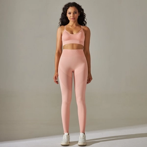 Front view of peach pink seamless high waist yoga leggings and cross strap sports bra set