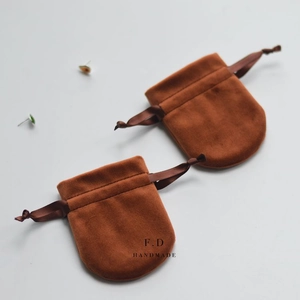 Detailed view of two brown velvet drawstring jewelry pouches with handmade printed text