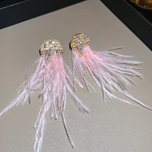 Macro detail of long pink feather tassel earrings with sparkling rhinestone studs