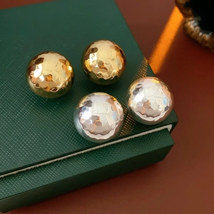 Dettaglio di orecchini a perno tondi martellati in oro e argento su scatola verde