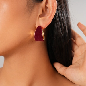 Close-up of wine red flocked geometric earring on ear with gold metal backing