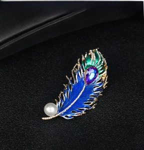 Detail of peacock feather brooch with colorful enamel, purple crystal and large white pearl