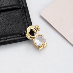 Macro detail of a golden elephant charm with a clear cubic zirconia heart on black leather