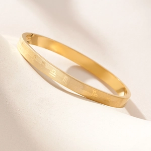 Minimalist gold titanium steel zodiac oval bangle with engraved symbols and secure clasp