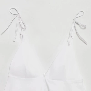 Sleeveless white V-neck tank top with adjustable shoulder bows and minimalist design