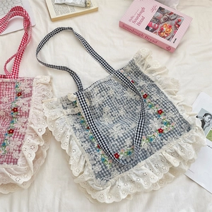 Detailed close-up of floral embroidery and white lace trim on a plaid canvas tote bag