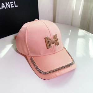 Close-up of pink baseball cap featuring a sparkling crystal M logo and rhinestone brim