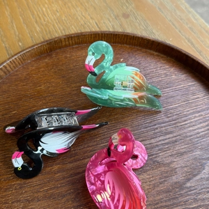 Detailed close-up of three acrylic flamingo hair claws in various candy marble colors