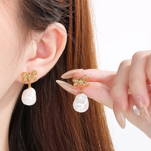 Elegant gold bow earrings with crystal inlay and dangling white pearl on model