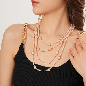 Détail d'un collier multicouche en perles roses avec cristaux et accents dorés élégants