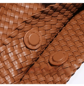 Macro detail of brown woven leather texture with circular buckle and precision stitching