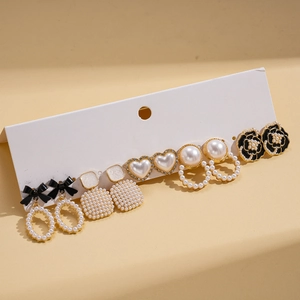 Detail view of 6-pair gold earring set with black bows, pearls and floral studs