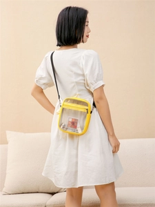 Detail of yellow transparent PVC jelly bag with black strap showing interior capacity
