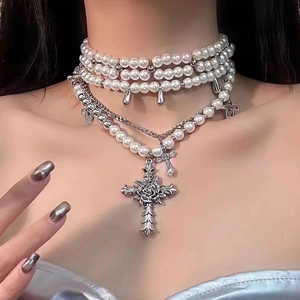 Detailed close-up of layered pearl necklace with silver cross and rose carved pendants