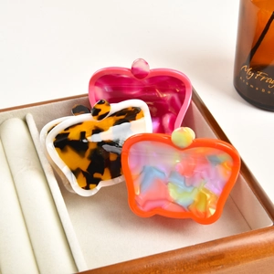 Three acetate fruit-style hair claws in magenta, tortoiseshell, and iridescent orange colors