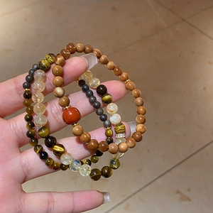 Close-up of beaded tiger eye and rutilated quartz bracelet with red agate charm