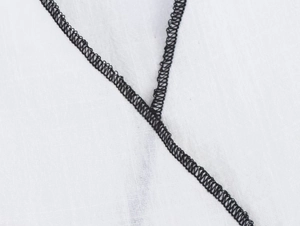 Détail de couture contrastée noire sur un tissu en coton et lin blanc de qualité