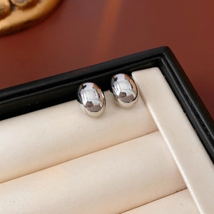 Silver oval metal stud earrings displayed in a luxury jewelry gift box