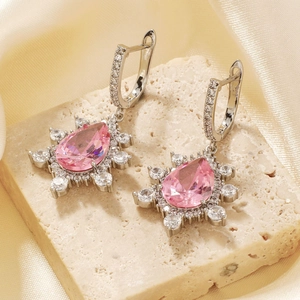Elegant silver pear-shaped pink zircon drop earrings on decorative stone and silk background