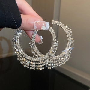 Dettaglio di orecchini geometrici in argento con strass multistrato e nappe scintillanti
