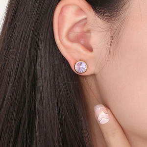 Gros plan de boucles d'oreilles rondes dorées avec cristal facetté violet élégant