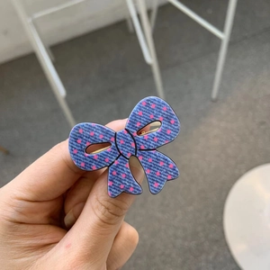 Denim bow hair clip with pink polka dots pattern held in hand for sweet Korean style