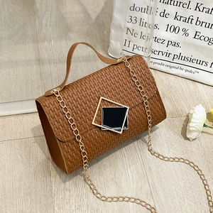 Vintage brown woven crossbody bag with golden chain and geometric buckle on wooden background