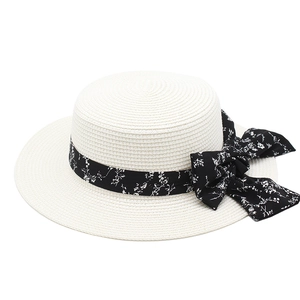 Detail view of woven straw sun hat featuring a large black floral ribbon bow