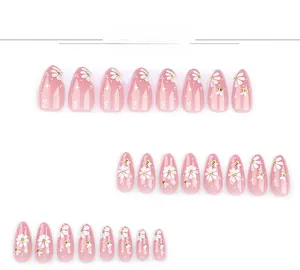 Detail view of pink almond press-on nails with daisy and honeybee patterns
