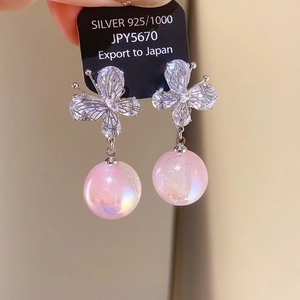 Detailed macro of 925 silver butterfly earrings with sparkling crystals and pink pearls