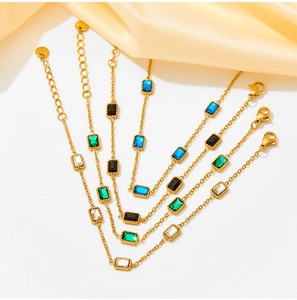 Macro view of gold stainless steel bracelets featuring square green, blue, black, and white zircon