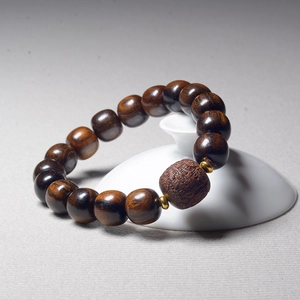 Handcrafted dark brown agarwood beaded bracelet with a central carved bead and gold accents