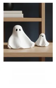 Detail van twee minimalistische witte keramische spookbeeldjes op een houten plank