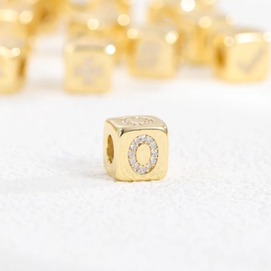 Macro shot of a 18k gold plated cube bead with letter O made of sparkling zircon stones